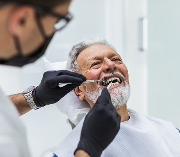 Older male patient having teeth treated by dentist