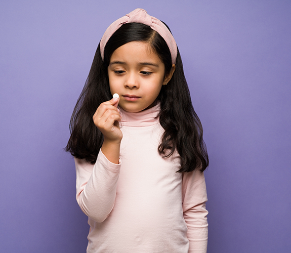 Little girl looking at a pill