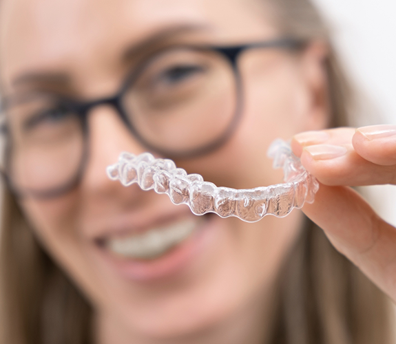 Woman with glasses holding Invisalign aligner
